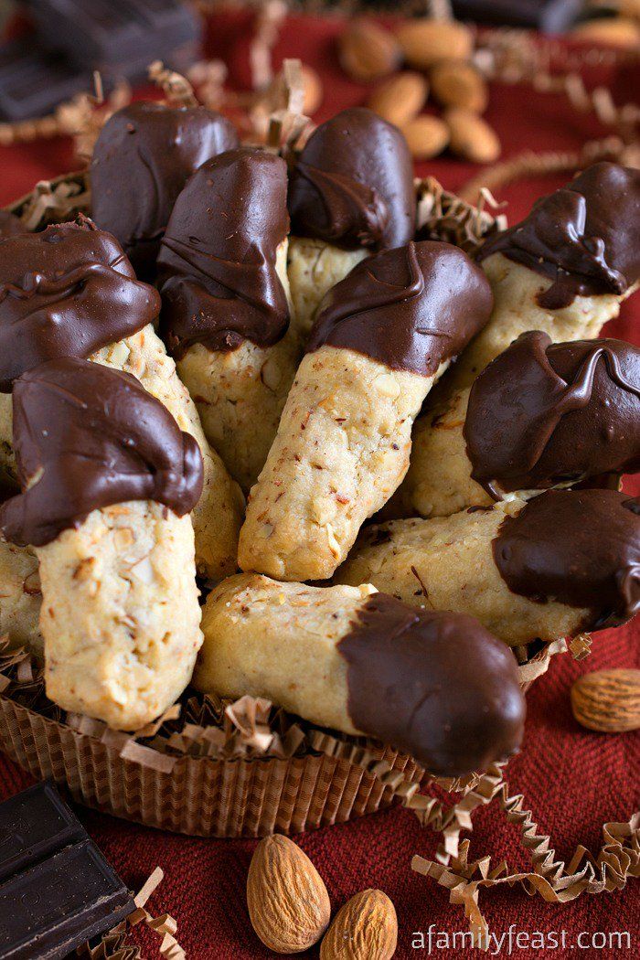 chocolate covered cookies in a basket with almonds on the side and nuts scattered around