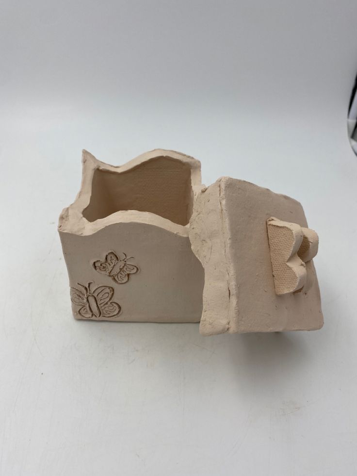 a small clay box with a butterfly on it