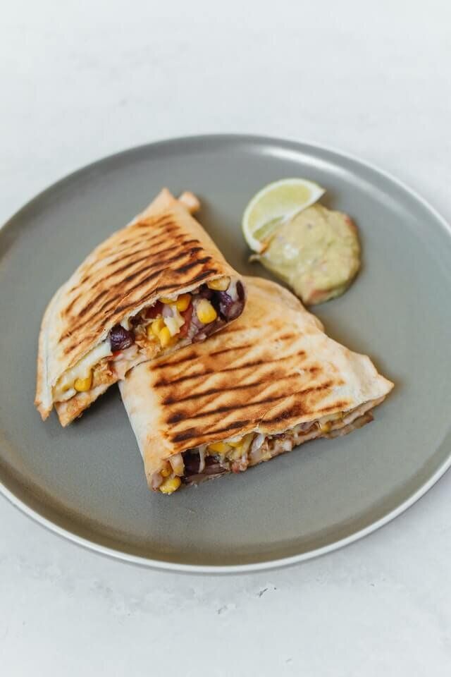 two quesadillas on a plate with a lemon wedge