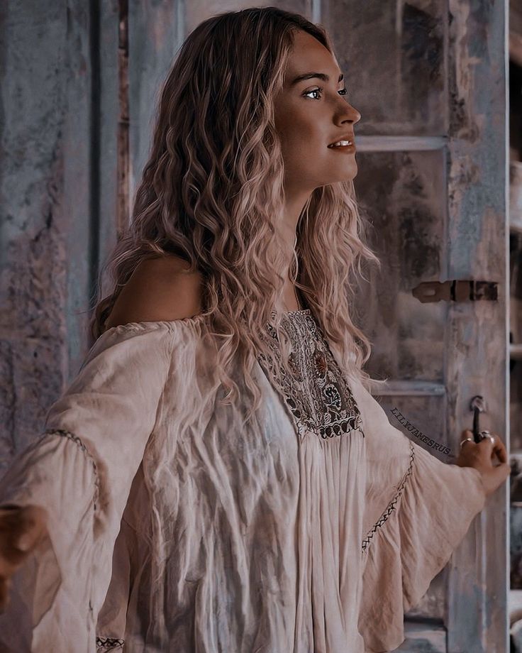 a woman with long hair wearing a white dress and holding her hand out to the side