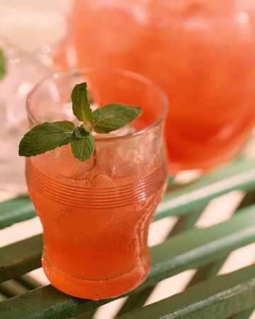 two glasses filled with watermelon and mint sitting on a green table next to each other