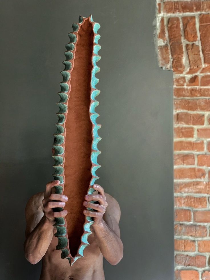 a man holding up a large piece of art made out of different shapes and sizes