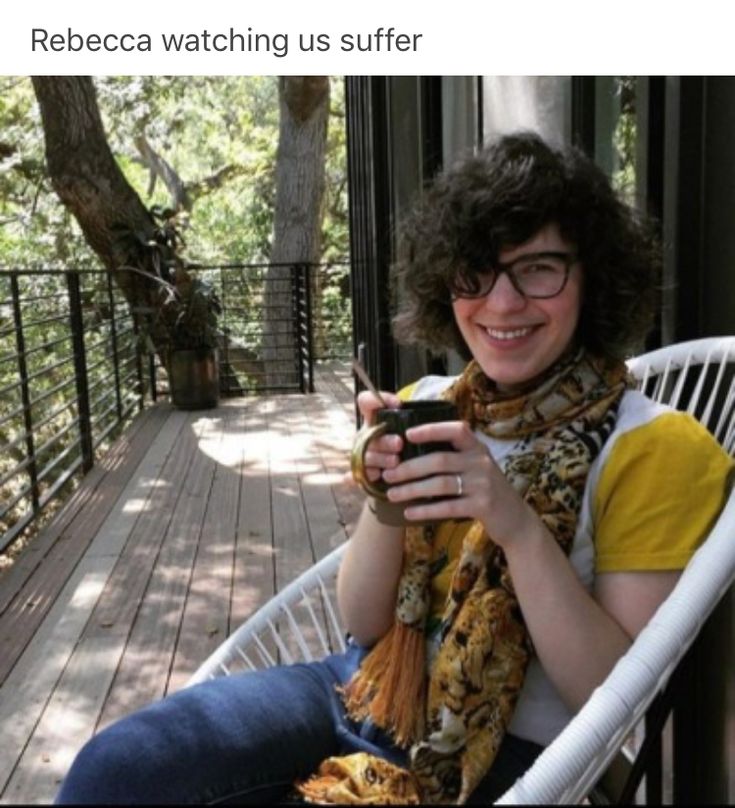 a woman sitting in a chair on a porch holding a cell phone and looking at the camera