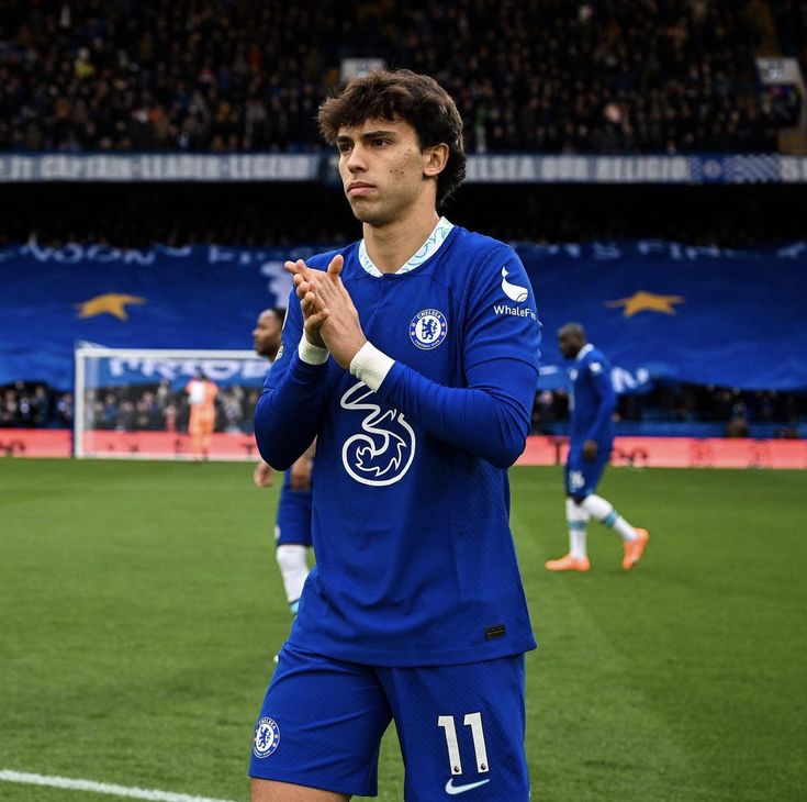 a man standing on top of a soccer field wearing a blue uniform and holding his hands together