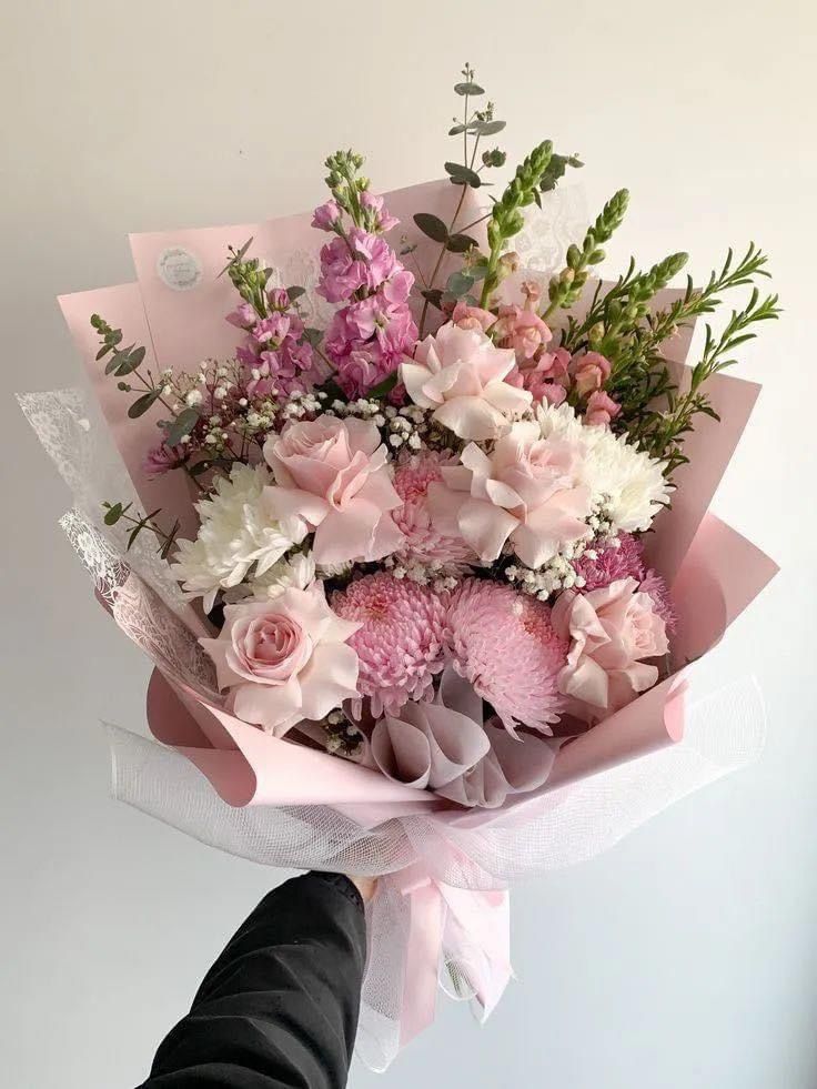 a person holding a bouquet of pink and white flowers