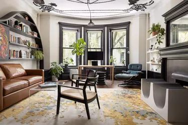 a living room filled with furniture and a fire place next to a window covered in plants