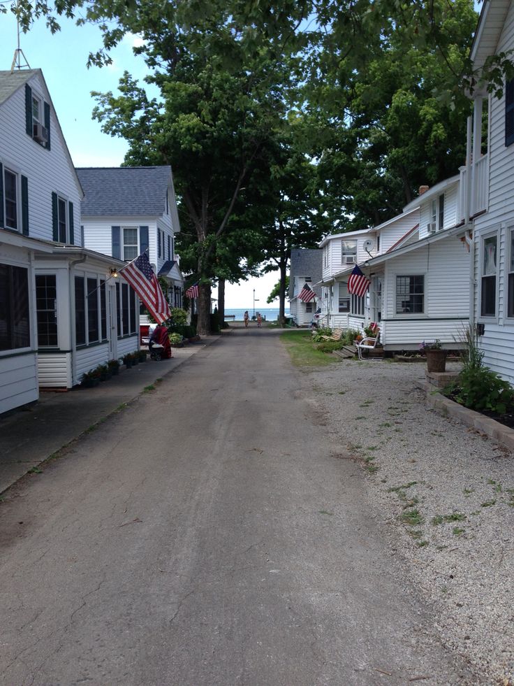 an empty street lined with white houses and american flags on the side of each house