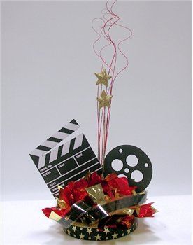 a movie clapper and some red flowers in a small bowl with streamers on the side