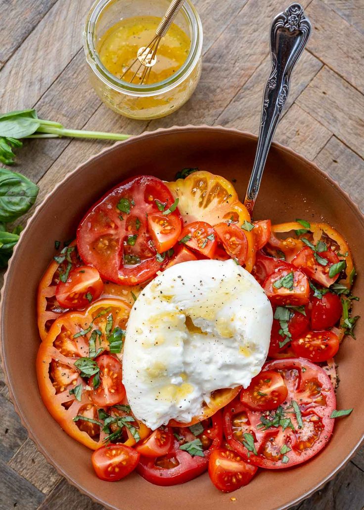 a bowl filled with tomatoes and eggs on top of a wooden table