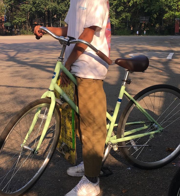 a man is standing next to his bike on the street with trees in the background