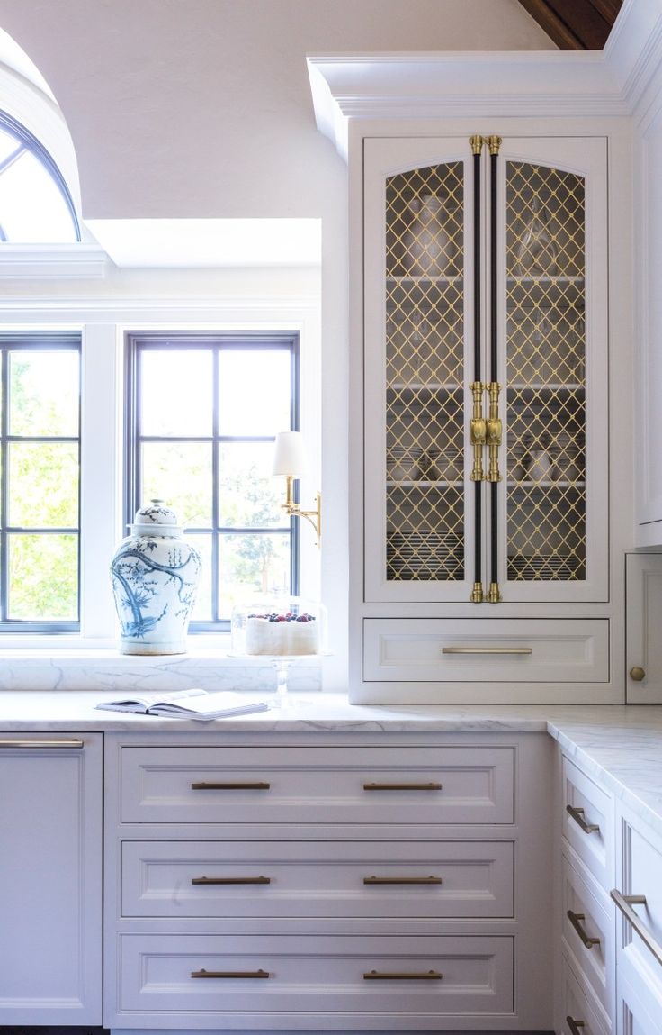 a kitchen with white cabinets and gold trimmings on the doors, windows, and counter tops