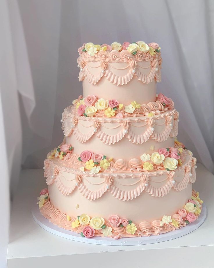 a three tiered cake with pink frosting and flowers on it's sides