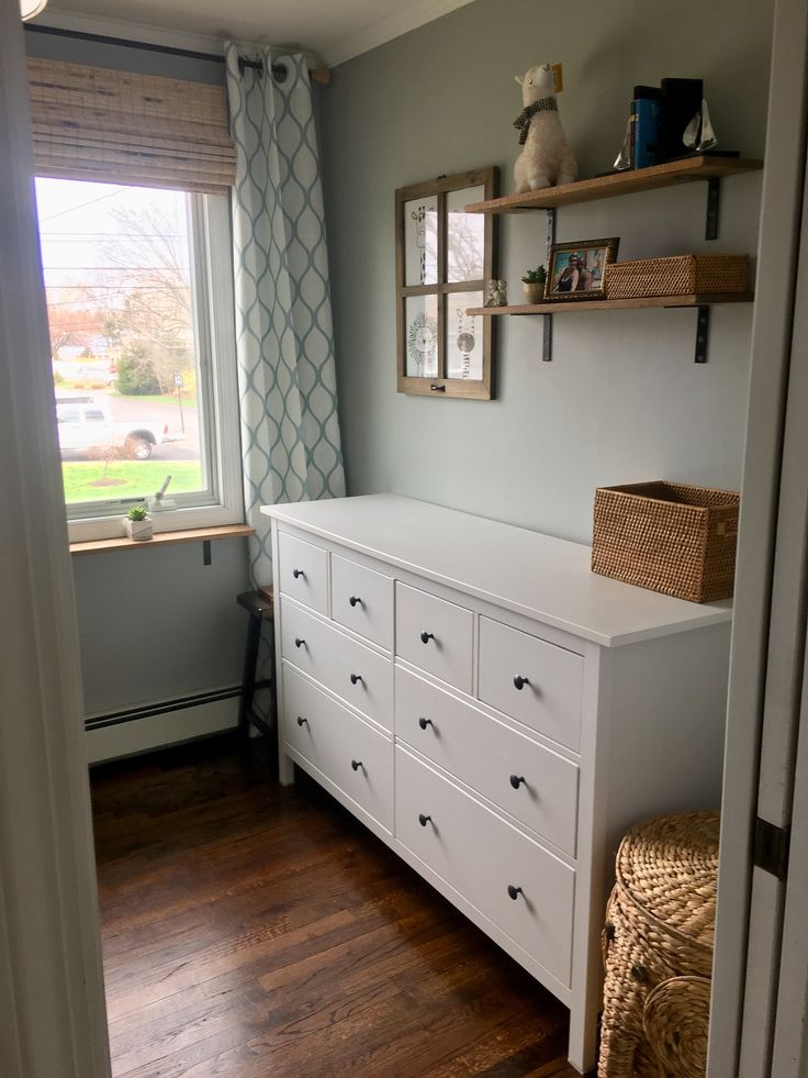 a white dresser sitting in a bedroom next to a window