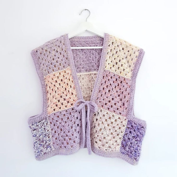 a crocheted vest hanging on a white wall