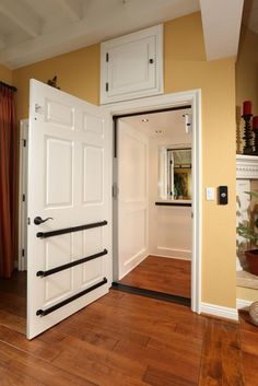 an open door leading into a living room with wood floors and white cabinets on either side