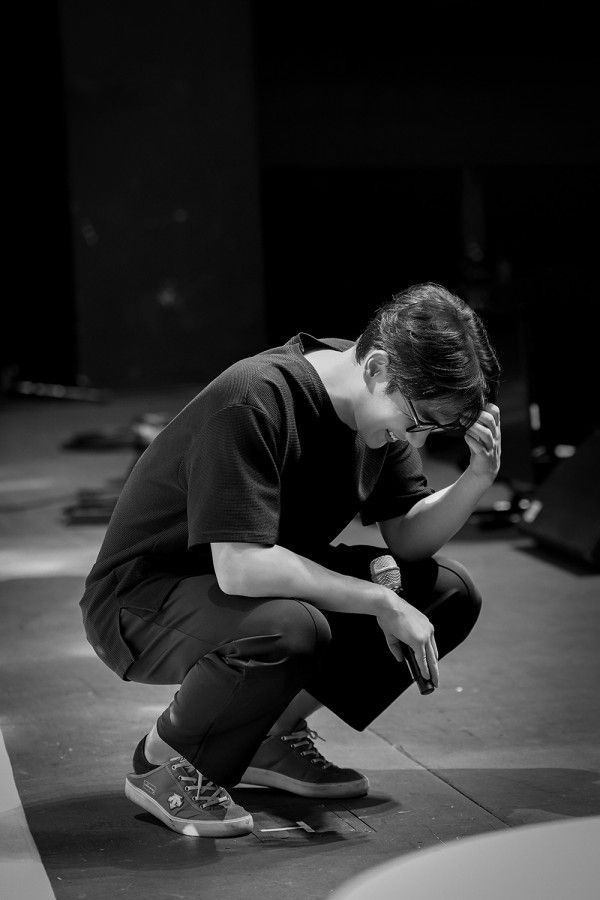 a woman squatting down on a skateboard with her hands to her face while looking at the ground