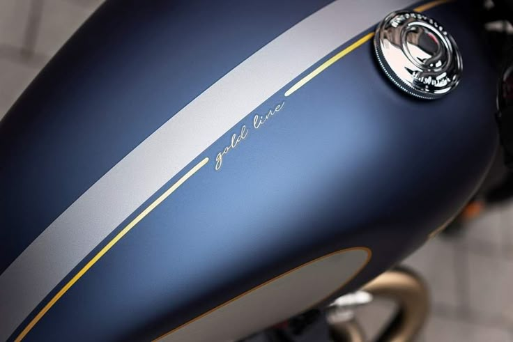 the front end of a blue motorcycle with gold trimmings and a logo on it