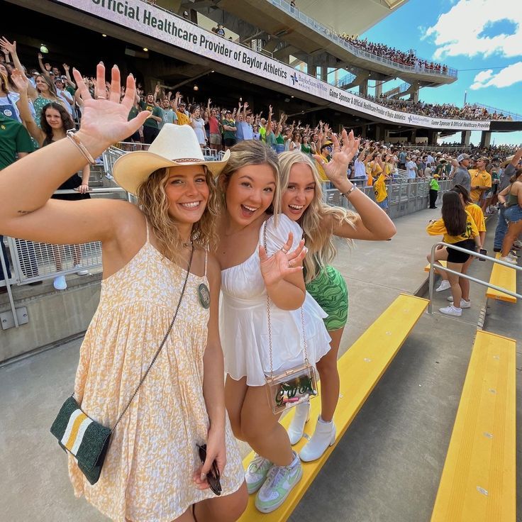 three girls are posing for the camera in front of a crowd at a sporting event