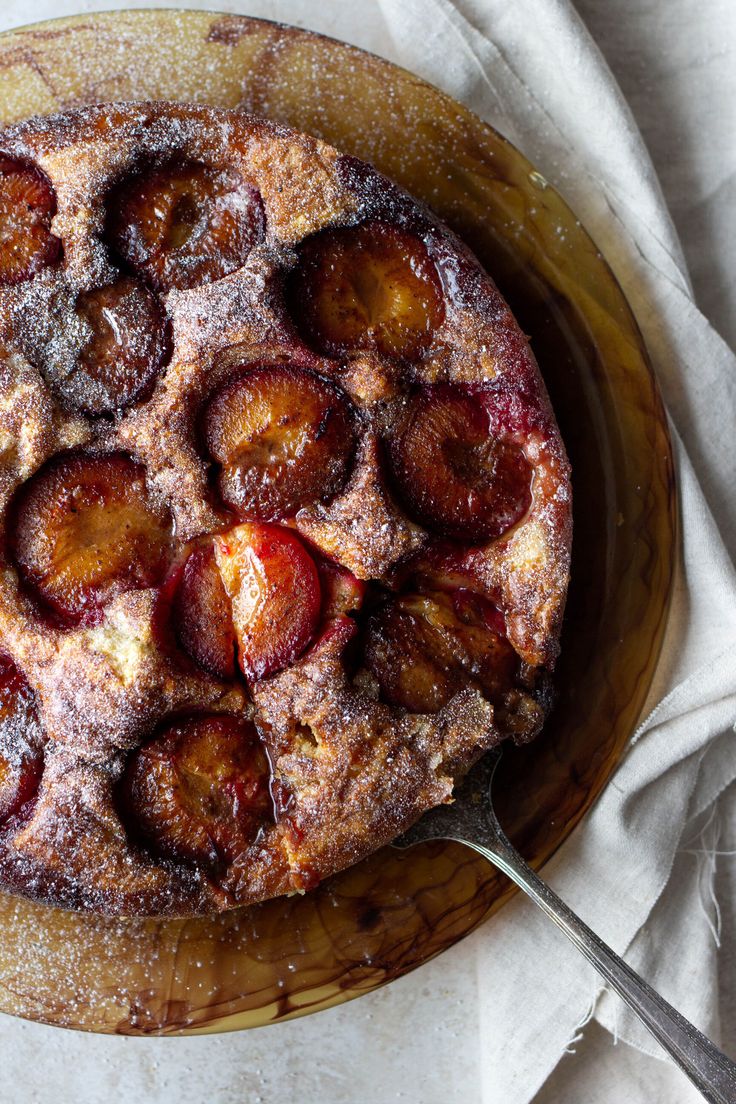 a dessert with fruit and powdered sugar is on a wooden platter next to a fork