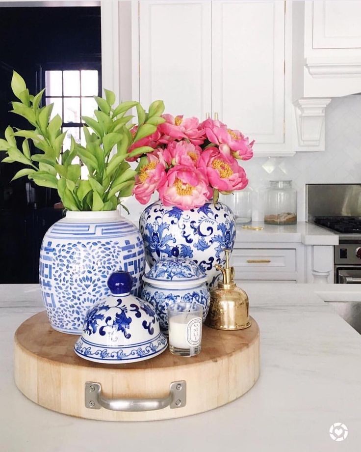 pink flowers are in blue and white vases on a kitchen counter with gold accents