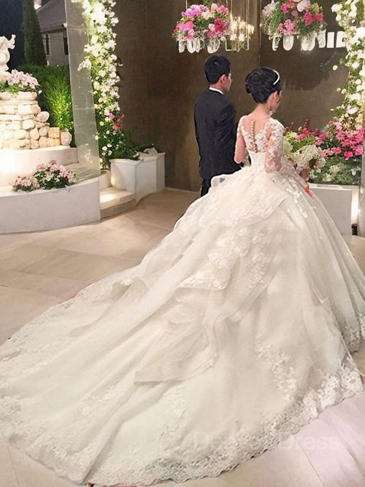 the bride and groom are looking at each other in their wedding gowns on display