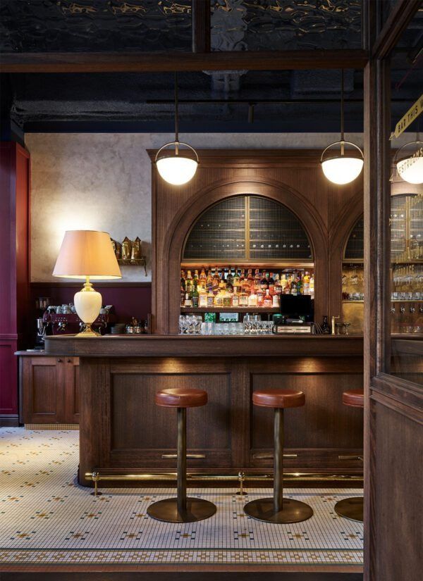 a bar with two stools in front of it and a lamp on the wall