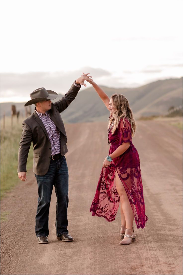 a man and woman dancing on a dirt road