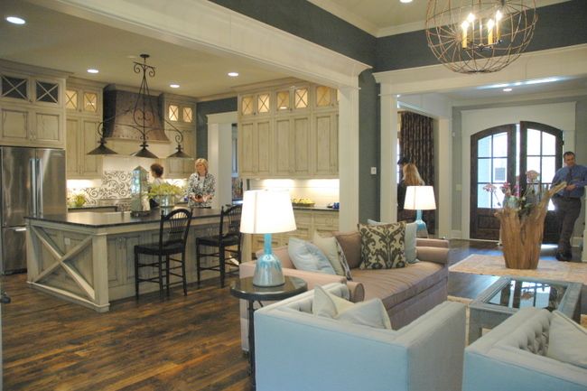 a living room filled with furniture next to a kitchen and dining room table in front of an open floor plan