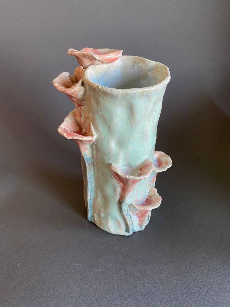 a ceramic vase sitting on top of a gray table next to a white wall and floor