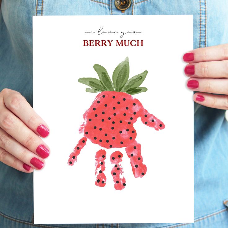 a woman holding up a card with a handprint of a strawberry on it that says berry much