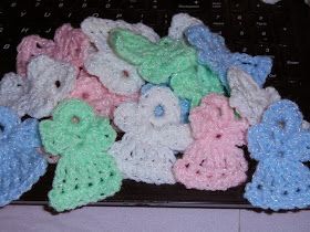 small crocheted flowers are arranged on a black table top, in pastel colors