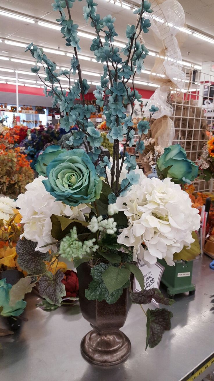 a vase filled with blue and white flowers on top of a metal table in a store