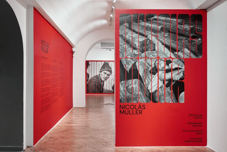 an art gallery with red walls and black and white artwork on the wall, including posters