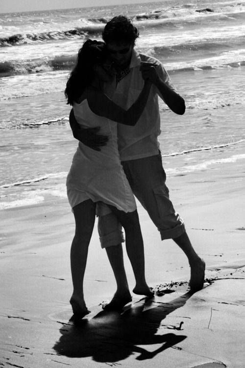 black and white photograph of two people hugging on the beach