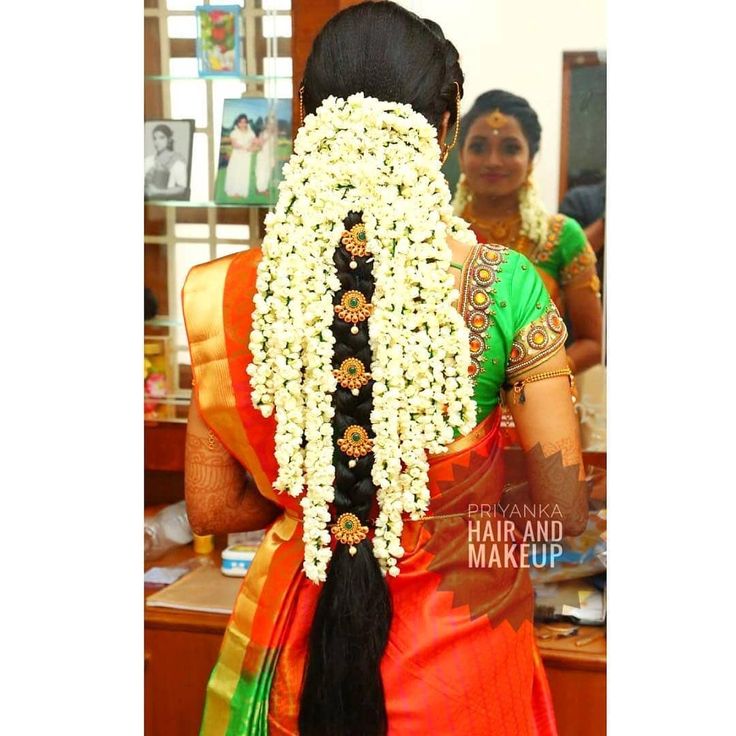 a woman is getting her hair done with flowers in the back and braided up