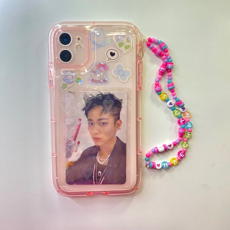 a cell phone case with a photo and beaded necklace attached to it on a white surface