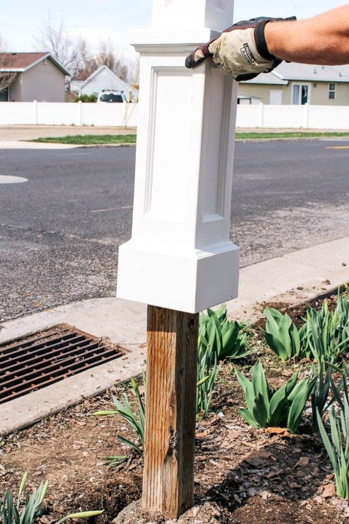 a person with gloves on their hands is fixing a white mailbox in the ground