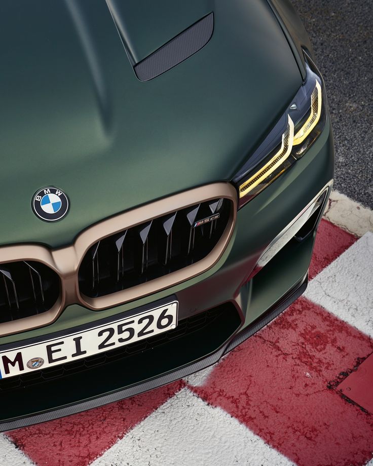 the front end of a green bmw car on a checkered red and white floor