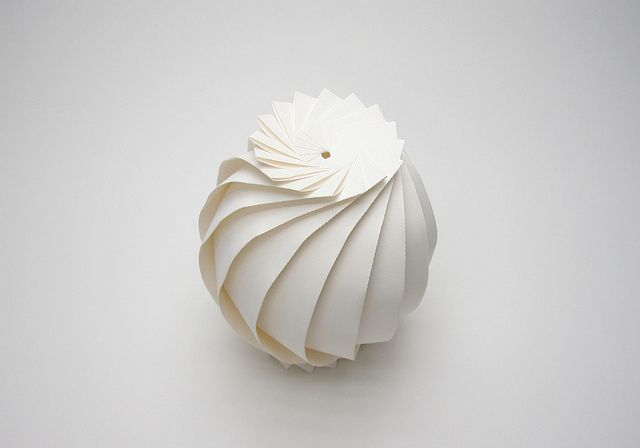 a white object is sitting on the floor and it looks like an origami ball