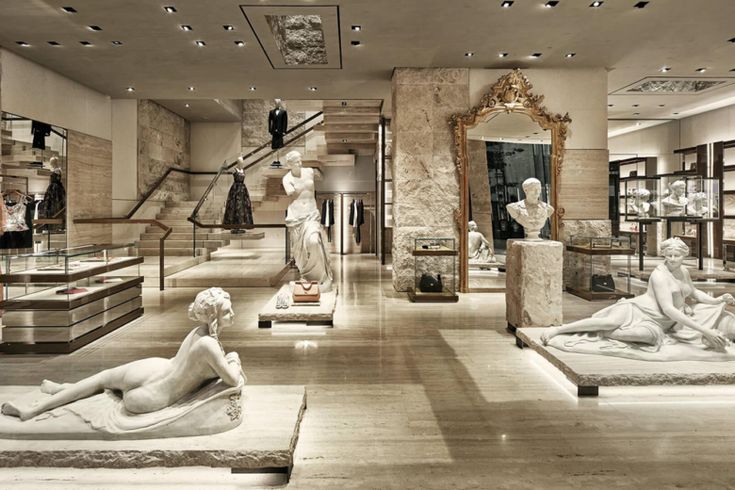 there are many statues on display in the room with bookshelves and glass cases