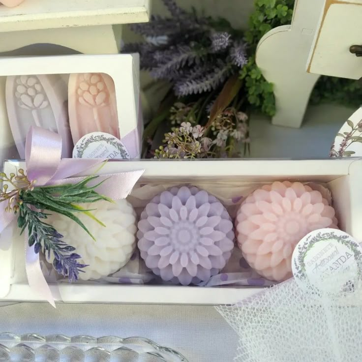 several soaps in a box with ribbons and flowers on the top one is lavender