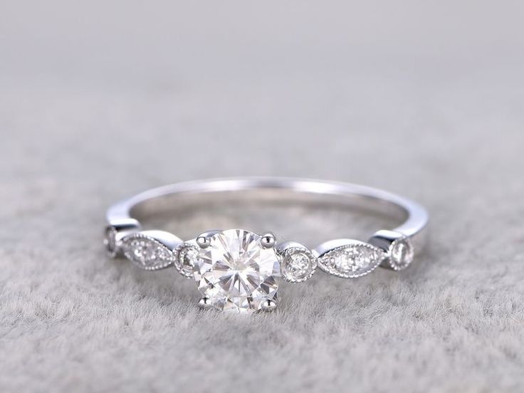 a white gold engagement ring with an oval cut diamond surrounded by three small round diamonds