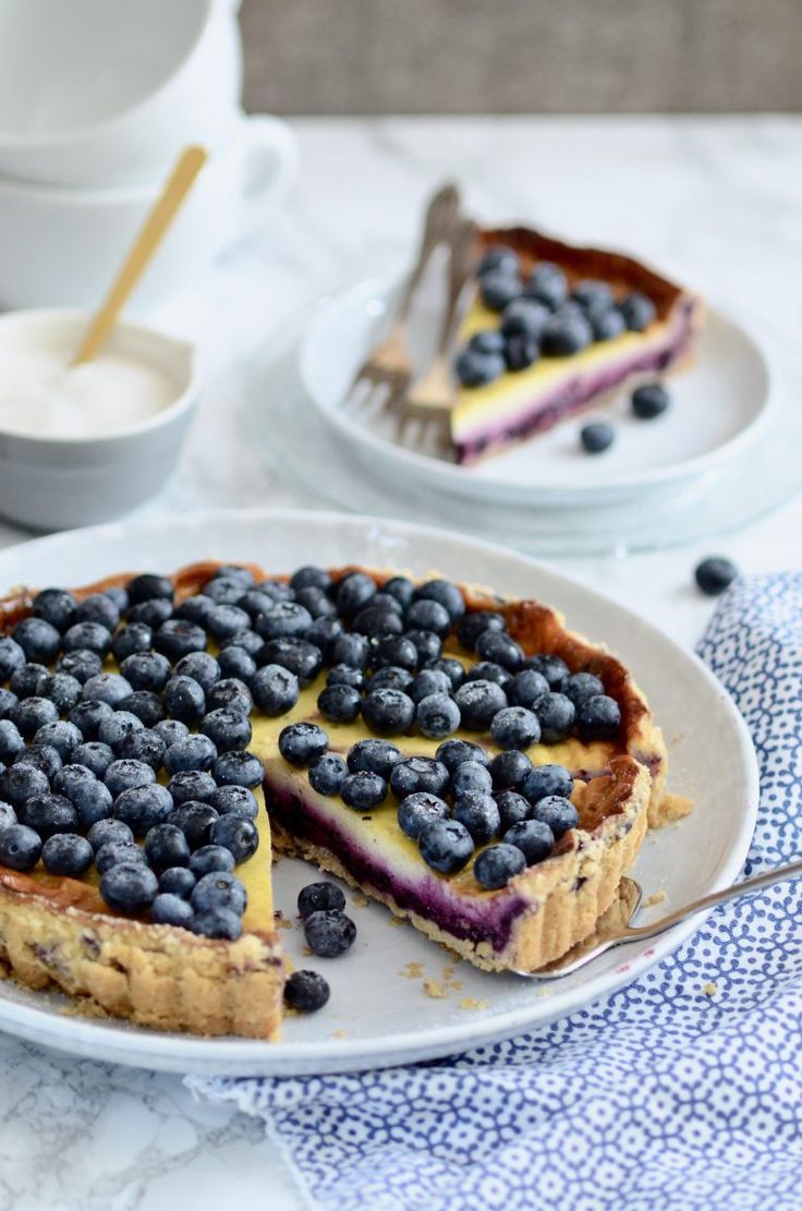 a blueberry cheesecake on a plate with a slice cut out and ready to be eaten