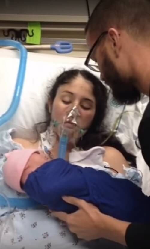 a man and woman are looking at a baby in a hospital bed