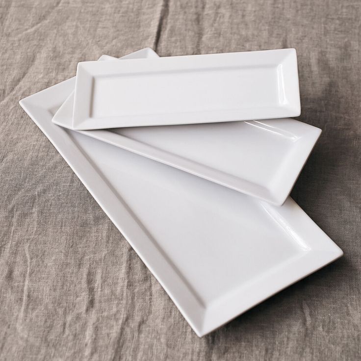 three white plates stacked on top of each other in the shape of rectangles