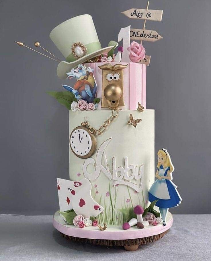 a birthday cake decorated with an alice in wonderland theme and clock on it's side