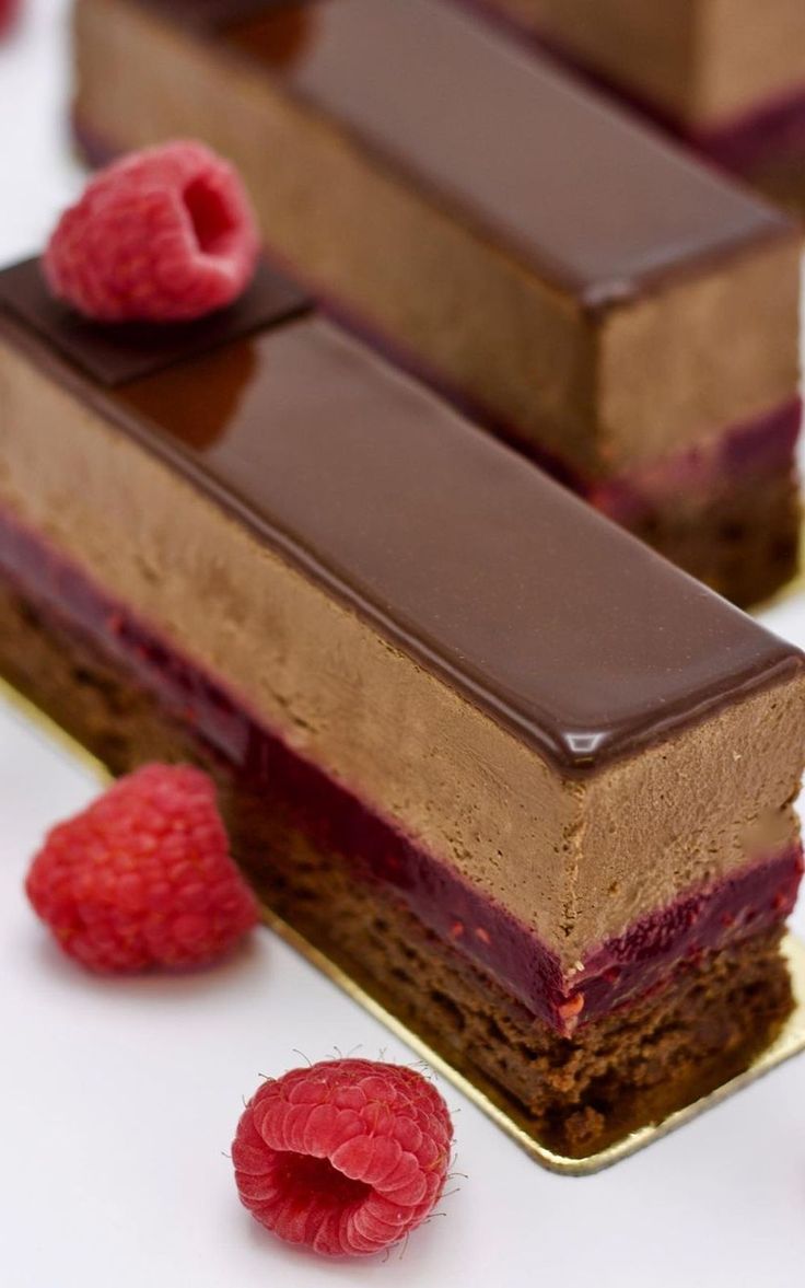 two pieces of chocolate cake with raspberries on the side