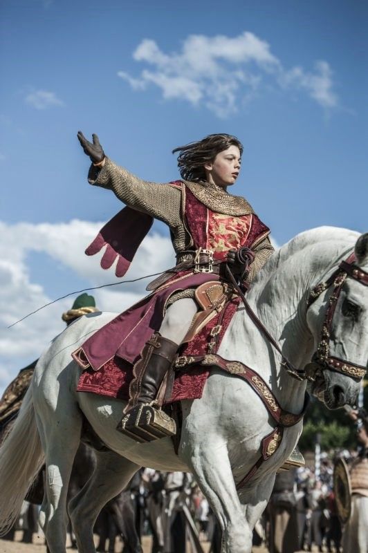 a woman riding on the back of a white horse in front of a group of people