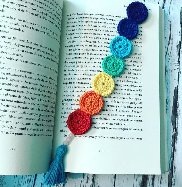 an open book with crocheted circles and tassels on top of it