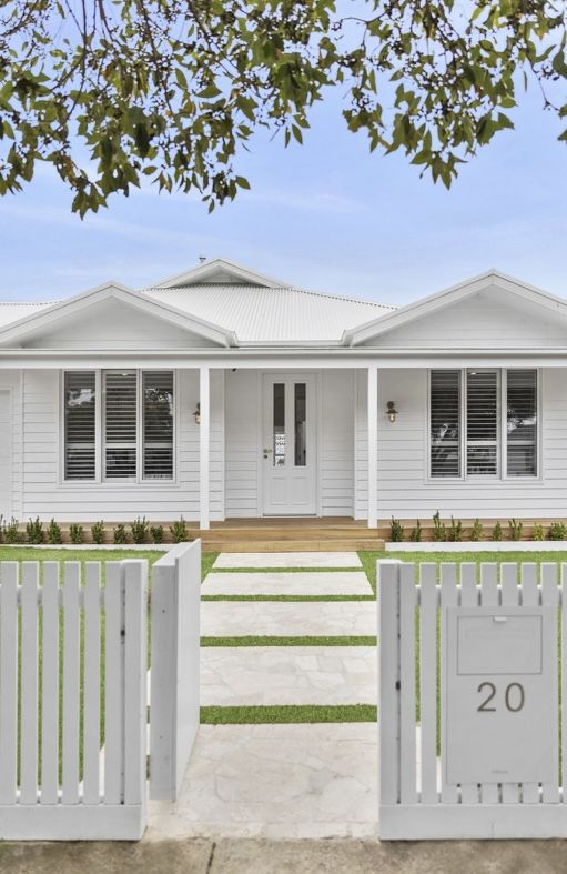 a white house that is next to a fence and grass area in front of it